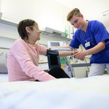 Ein Pflegefachmann misst den Blutdruck einer älteren Patientin im Krankenhaus.