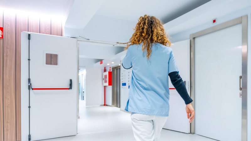 Eine Krankenschwester läuft einen Klinikflur entlang.