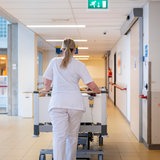 Eine Krankenpflegerin schiebt ein Bett über einen Klinikflur (Symbolbild)