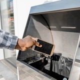 Ein Mann wirft ein Smartphone in eine Mülltonne.