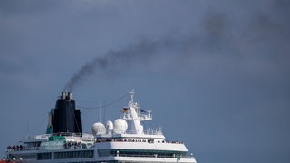 Der Schornstein eines Kreuzfahrtschiffes stößt dunklen Rauch aus.