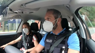 Zwei PolizistInnen vom Kriminaldauerdienst im Auto auf Streife.