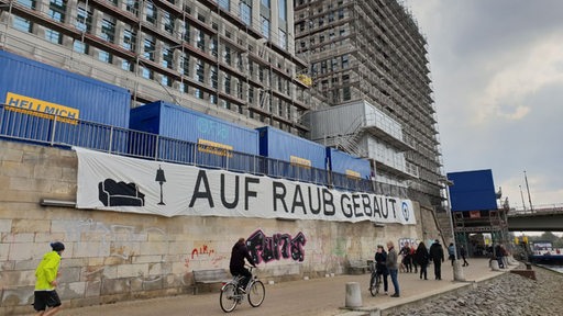 Protestplakat an der Schlachte am Neubau der Spedition Kühne und Nagel mit der Aufschrift "Auf Raub gebaut".