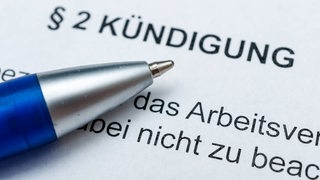 Auf einem Zettel steht Kündigung. Daneben ein blauer Kugelschreiber.