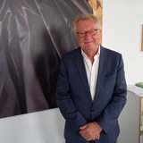 A man is standing in front of a dark painting.