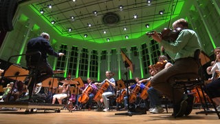 Ein Orchester auf der Bühne der Glocke mit Dirigent und schöner Hintergrundbeleuchtung. 