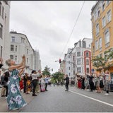 Mehrere Personen stehen sich auf einer Straße gegenüber und klatschen.