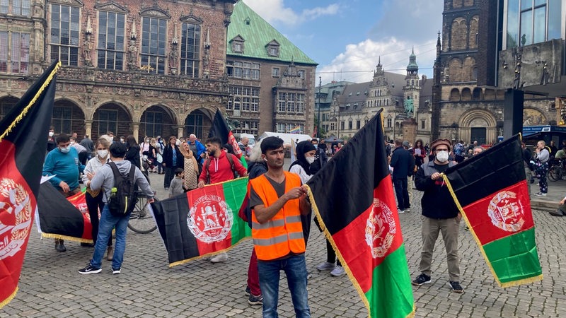 Menschen stehen mit afghanischen Flaggen auf dem Bremer Marktplatz.
