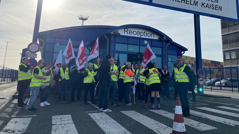 Menschen in Warnwesten halten Fahnen mit der Aufschrift "Verdi".