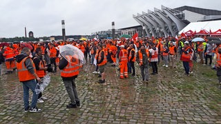 Warnstreik der Bremer Baubranche: Kundgebung auf der Bremer Bürgerweide mit streikenden in orangen Warnwesten.