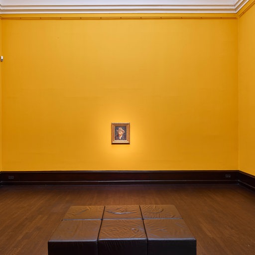 Ein Bild hängt alleine in einem gelb gestrichenen Saal