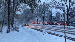 Autos sind auf der verschneiten Kurfürstenallee unterwegs.