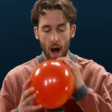 Ein Mann hält einen aufgeblasenen Luftballon vor sich.
