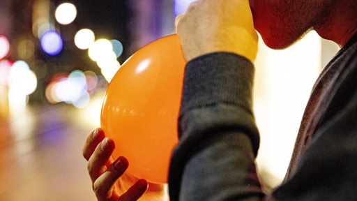 Ein Jugendlicher atmet durch einen Ballon Lachgas ein