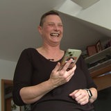 Eine Frau telefoniert bei sich zu Hause und lacht