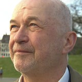 Ein Mann blickt mit leicht zugekniffenen Augen zur Seite und hoch