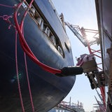 Die Landstromkabel eines Containerschiffs sind mit einer verfahrbahren Steckdose entlang dem Kai verbunden.