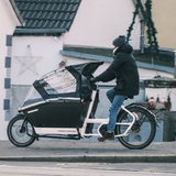 Ein Mann fährt mit einem Lastenrad auf einem Radweg.