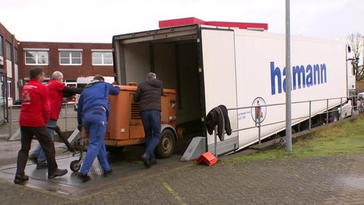 Personen befüllen einen LKW mit Gütern.