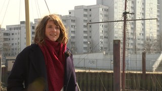 Die junge Autorin Laura Cwiertnia steht in Bremen Nord vor einer Hochhaussiedlung. 