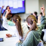 Schüler sitzen in einem Klassenzimmer und melden sich.