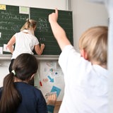 Schüler einer Grundschule arbeiten in einem Klassenzimmer an Mathematikaufgaben. 