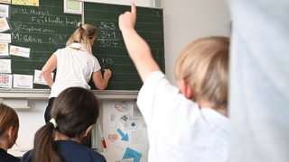 Schüler einer Grundschule arbeiten in einem Klassenzimmer an Mathematikaufgaben. 