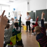 Schüler einer Grundschule recken ihre Finger nach oben.