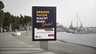 Ein Plakat steht an einem Fußweg.