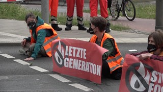 Aktivisten von der "Letzten Generation" sitzen auf einer Straße