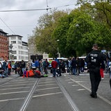 Eine Gruppe von Demonstrierenden auf einer Kreuzung, im Vordergrund ein Polizist.