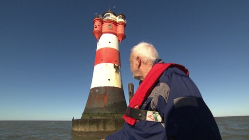 Manfred Benhof vom Förderverein ist auf einem Schiff und guckt auf den Leuchtturm Roten Sand. 