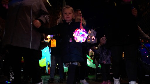 Ein Kind trägt eine Laterne in der Hand.