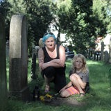 Eine Frau mit blauen Haaren sitzt mit ihrer Tochter an einem Grab auf dem jüdischen Friedhof in Hastedt