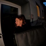 Eine Frau steht vor einer Haustür und klingelt.