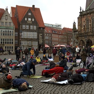 Menschen liegen mit Decken und Luftmatratzen auf dem Bremer Marktplatz
