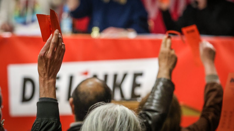 Delegierte heben bei einer Abstimmung auf dem Außerordentlichen Landesparteitag der Partei Die Linke ihre Stimmkarten. 