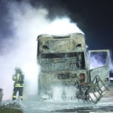 Ein Feuerwehrmann steht neben einem ausgebrannten und immer noch rauchenden Lkw.