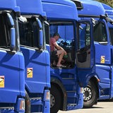 Ein Lkw-Fahrer sitzt im Führerhaus eines Lkw, der in einer Reihe mit anderen Lkw steht.