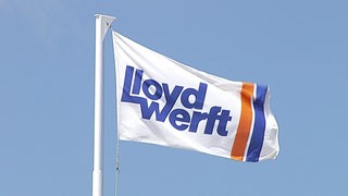 Ene Fahne weht vor blauem Himmel. Darauf die Aufschrift "Lloyd Werft".