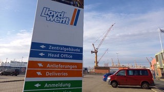 Ein Schild steht vor einem Hafengelände.