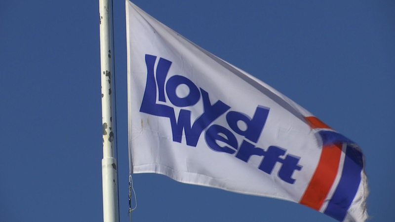 Eine Flagge mit dem Logo der Lloyd-Werft weht im Wind. 