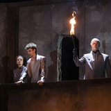 In einer Theaterkulisse stehen vier Schauspieler auf einer Balustrade.