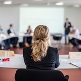 Rückenansicht einer Frau in Businesskleidung in einer Besprechung.