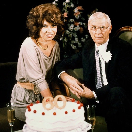 Evelyn Hamann und Loriot sitzen vor einer Geburtstagstorte mit einer 60 darauf.