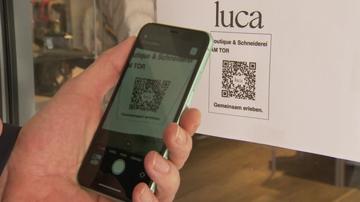 Eine Person scannt den QR Code der Luca App ein. 