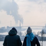 Passanten betrachten bei kühlem Wetter die Köhlbrandbrücke und die umliegenden Industrieanlagen im Hamburger Hafen.