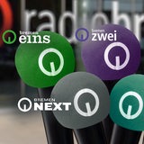 Fünft unterschiedlich farbige Mikrofone mit den Logos von Bremen Eins, Bremen Zwei, Bremen Vier, Bremen Next und Cosmo.
