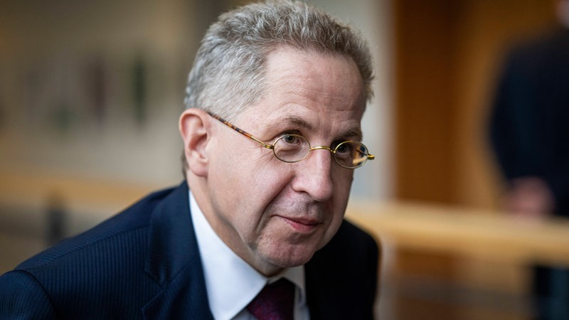 Hans-Georg Maaßen mit Brille und im Anzug in einem Gebäude.