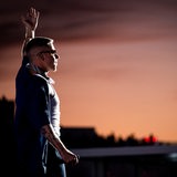 Der Rapper Macklemore steht auf einer Bühne und hebt den linken Arm.